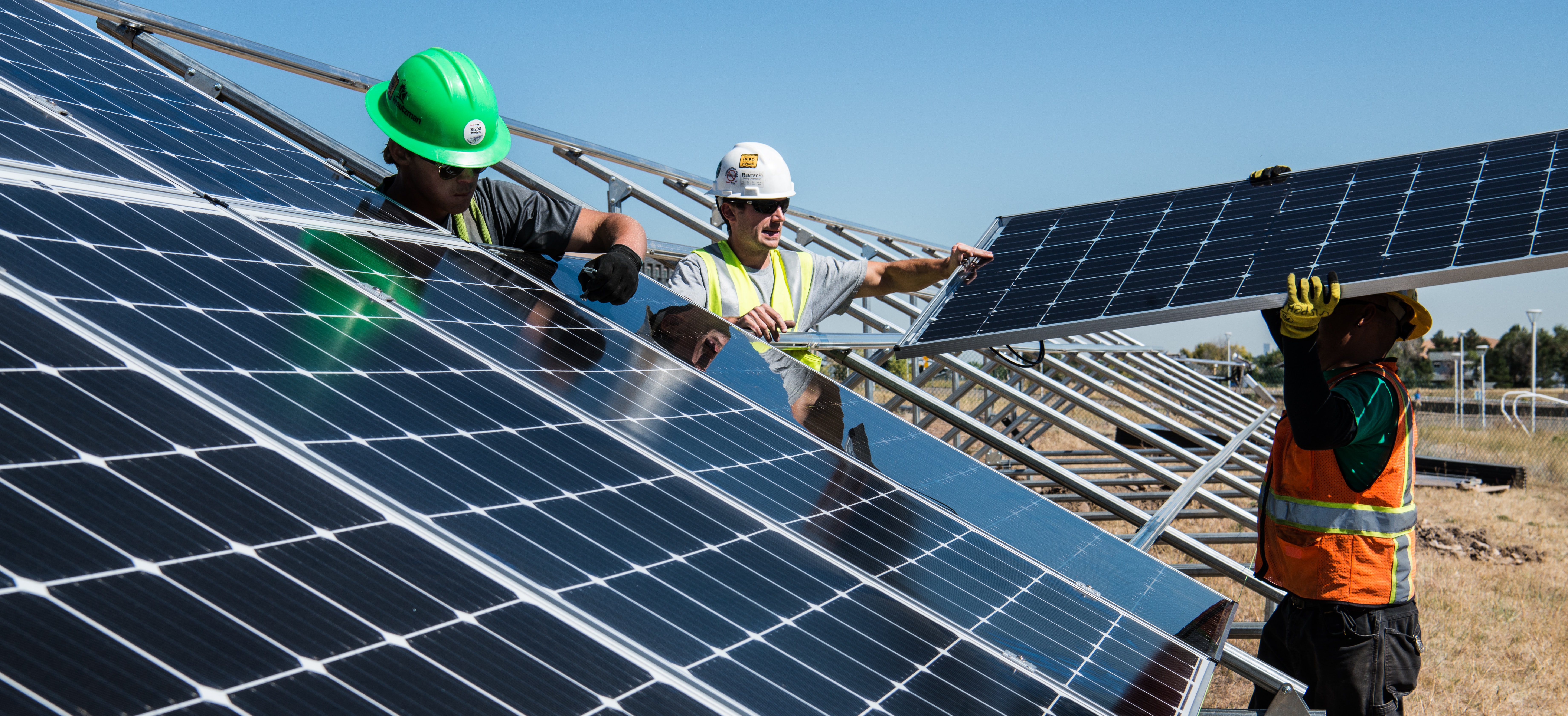 Trois hommes installent des panneaux solaires