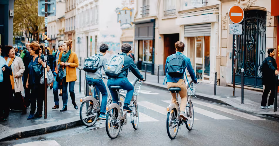 Trois jeunes se déplacent en vélo dans les rues.