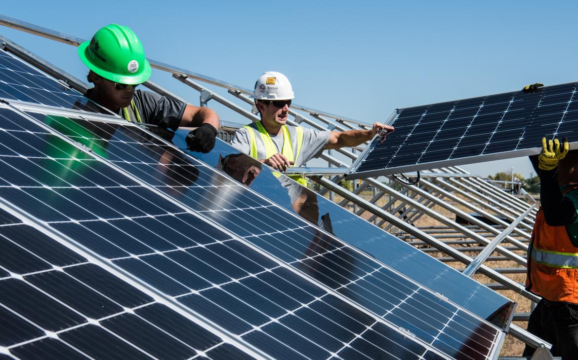 Trois hommes installent des panneaux solaires