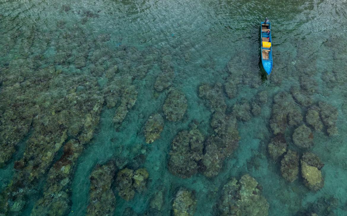Vue aérienne d'un bateau entouré de coraux, Maluku, Indonésie