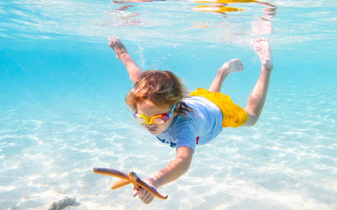 Enfant qui nage et qui tient une étoile de mer 