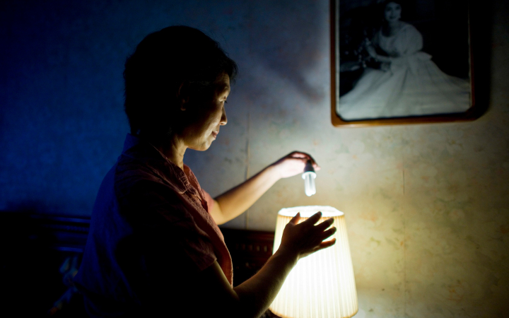Femme changeant son ampoule basse consommation dans le cadre de la campagne "20 ways to 20%" du WWF (Chine)