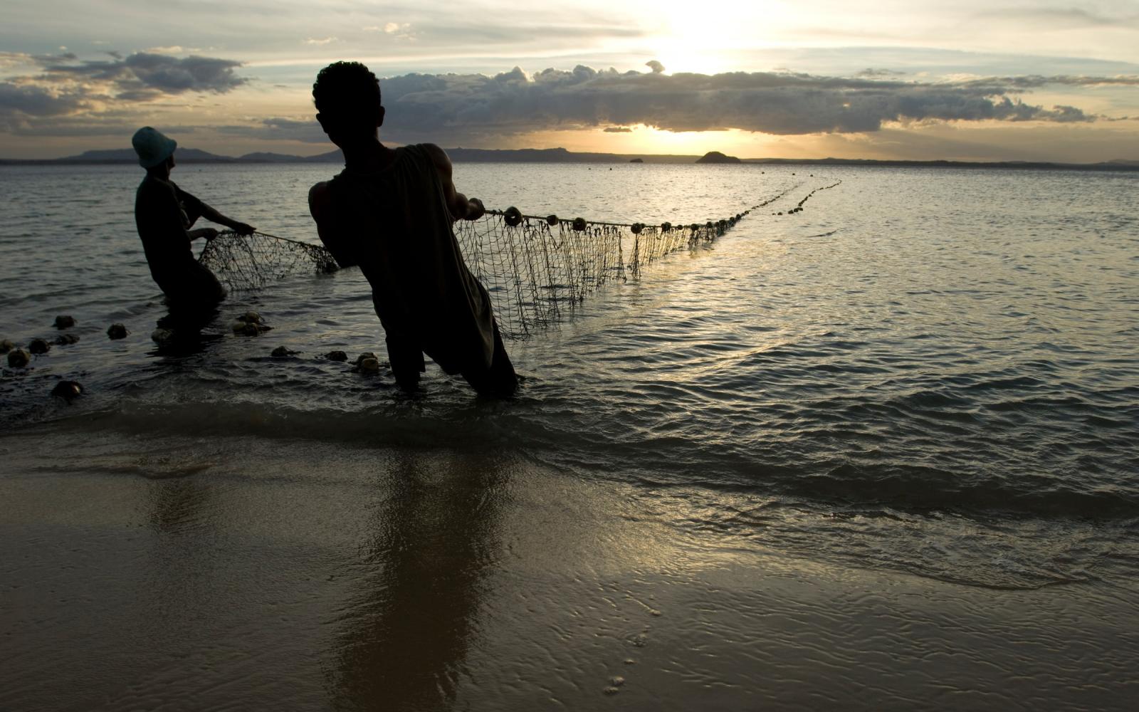 Des pêcheurs sortent leurs filets de l'eau au crépuscule, plage de Ramena à Antsiranana, Nord de Madagascar