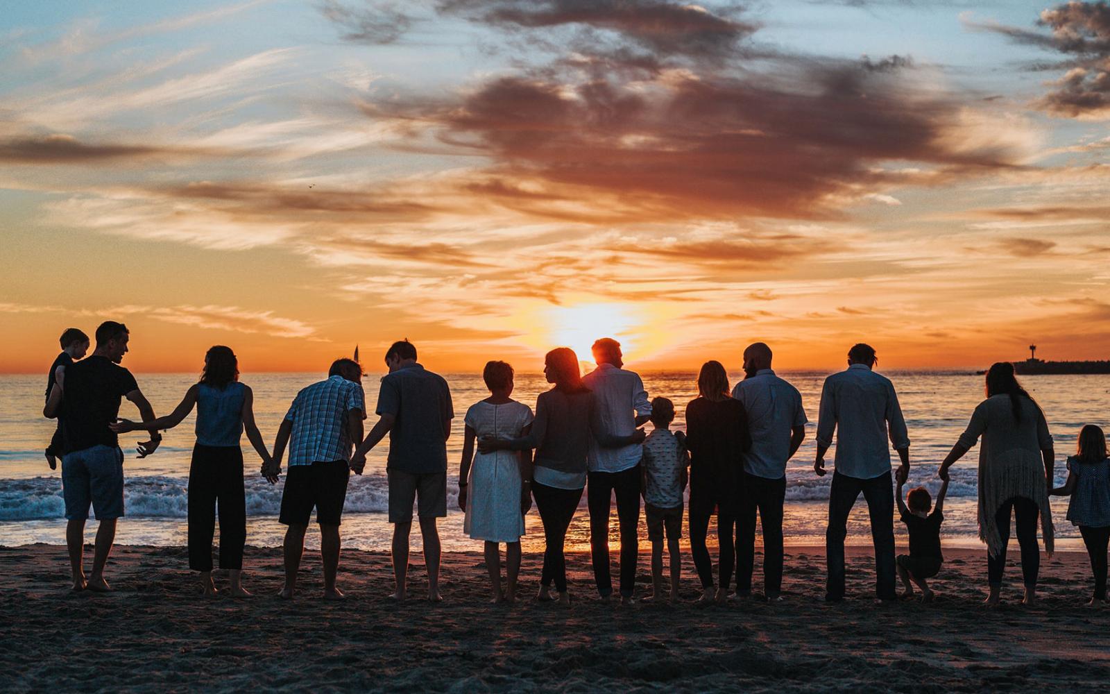 Groupe de gens regardant la mer au coucher de soleil