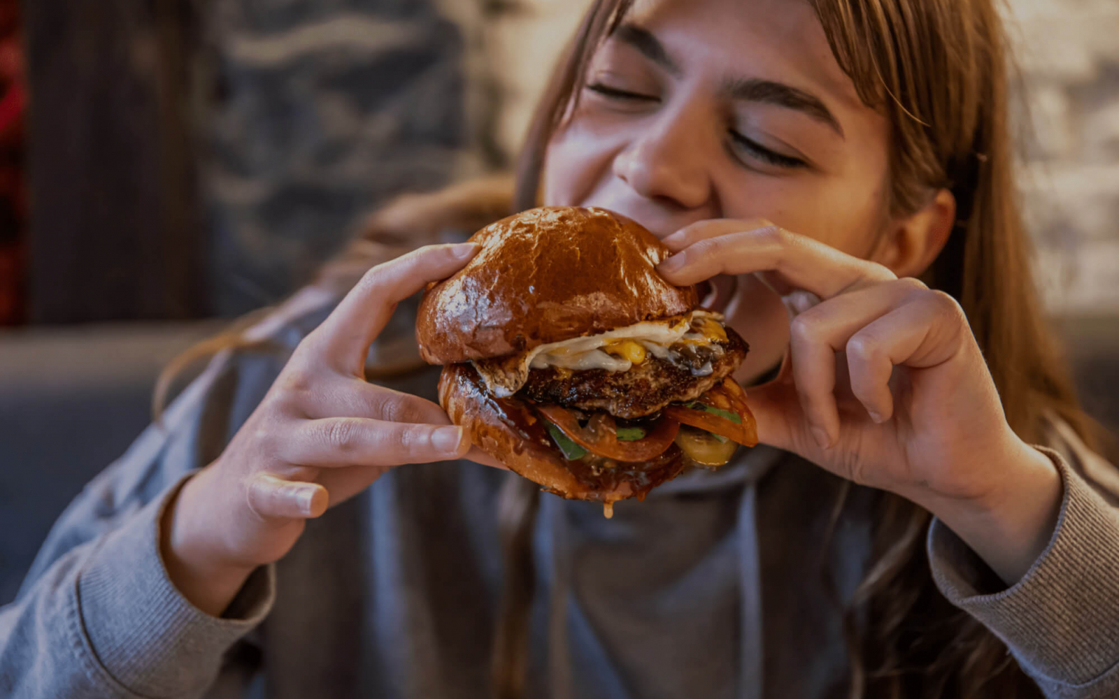 Jeune fille mangeant un hamburger appétissant, défi au mythe des protéines animales
