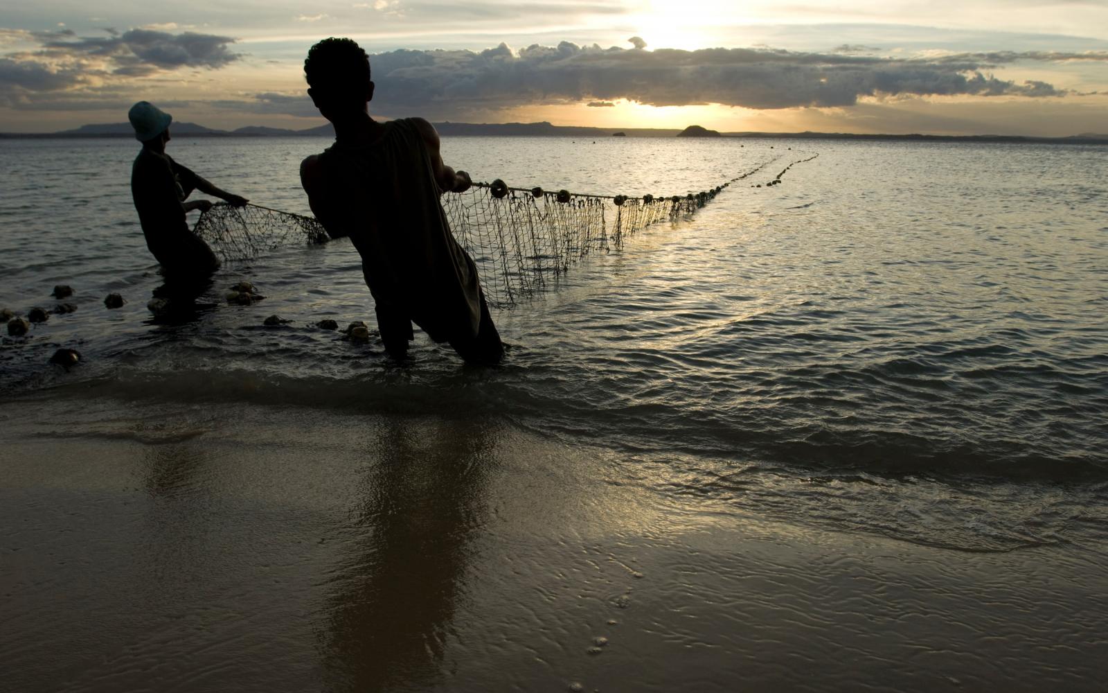 Des pêcheurs sortent leurs filets de l'eau au crépuscule, plage de Ramena à Antsiranana, Nord de Madagascar