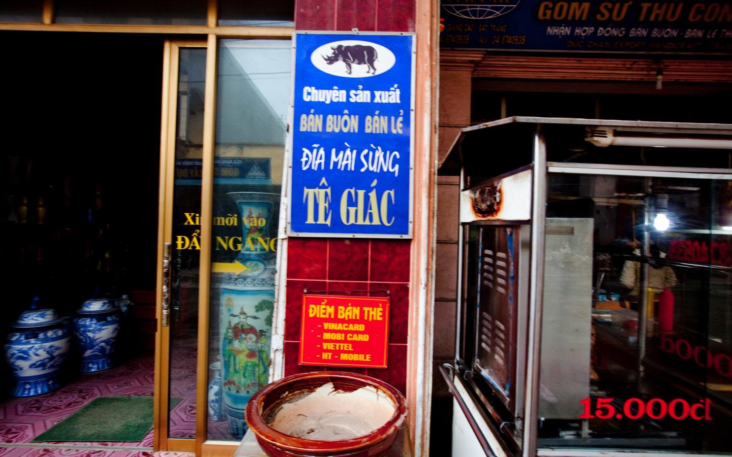 Un panneau devant un magasin de poterie dans le village de Bat Trang à la périphérie de Hanoi, au Vietnam, met en avant le fait qu'il ait à la vente de la poudre de corne de rhinocéros pour la consommation