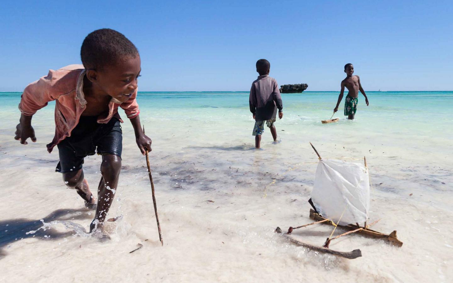 Enfants malgaches en train de jouer avec un bateau en bois dans l'Océan Indien