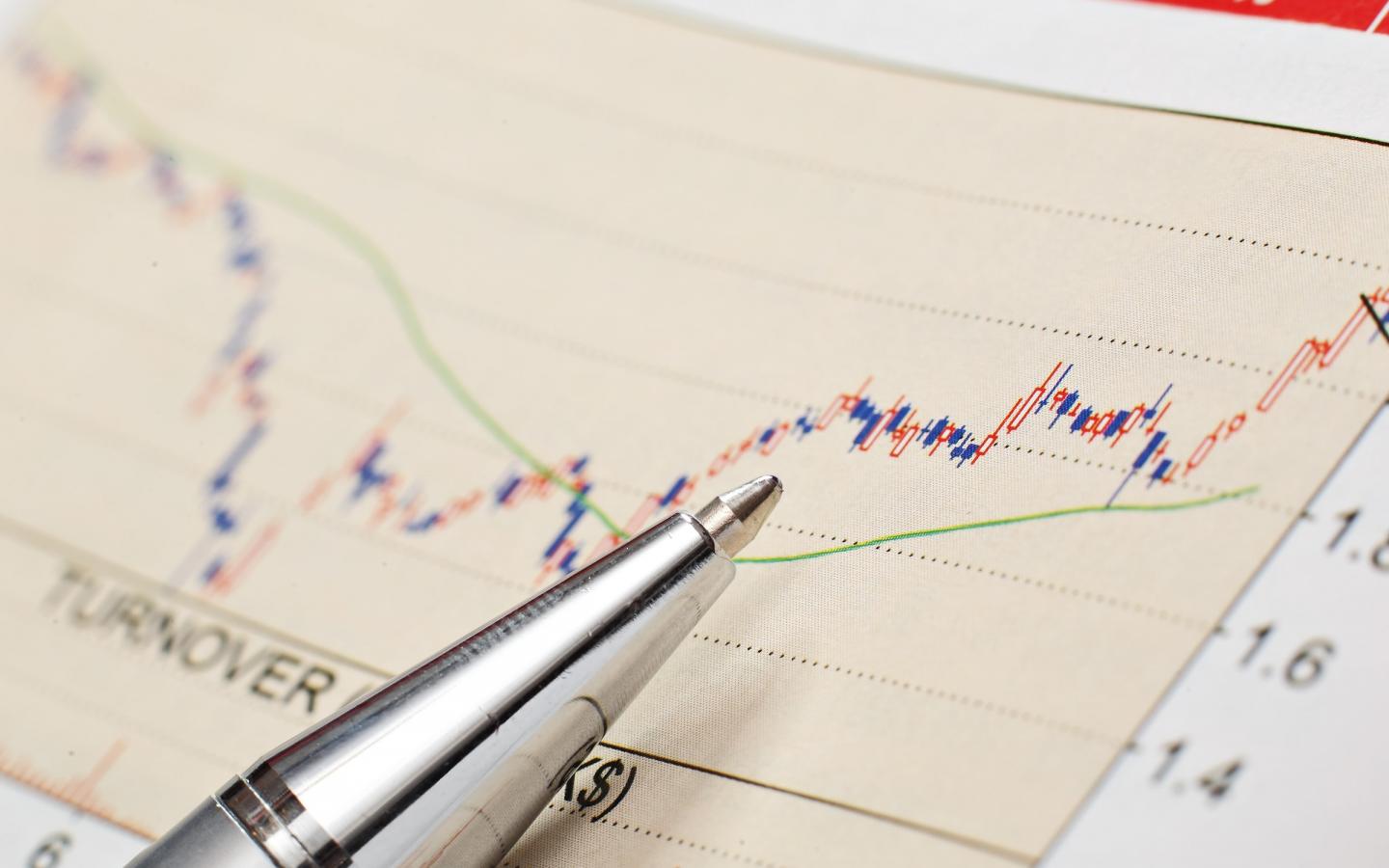 Graphique financier avec un crayon posé dessus représentant la bourse et les investissements