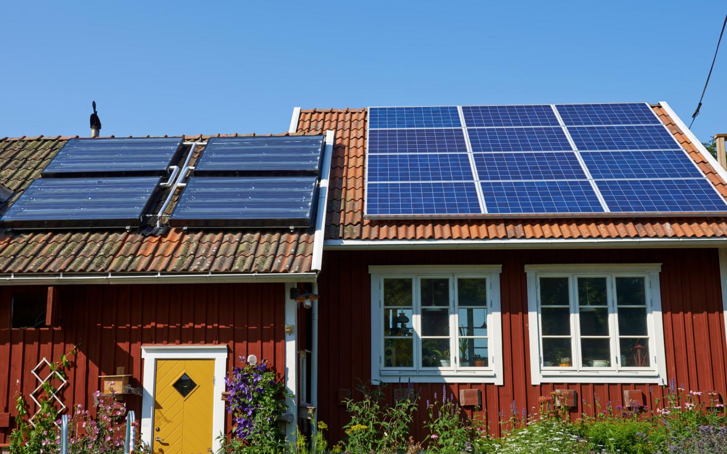 Panneaux solaires sur le toit d'un cottage rouge (Suède)