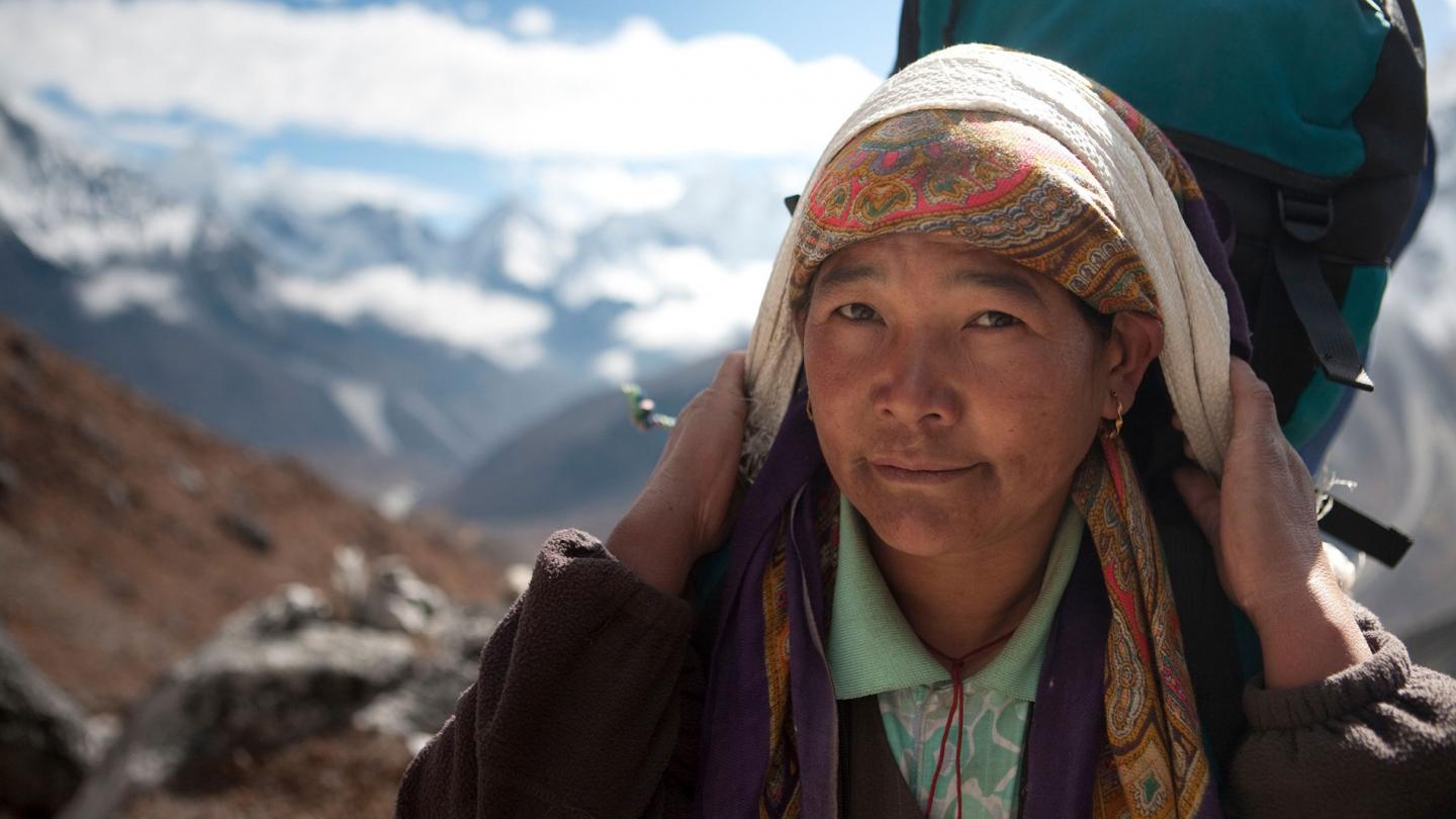 Femme portant un sac à dos lourd sur la route de Dengboche à Tuckla Pass, dans la région de l'Everest de l'Himalaya au Népal