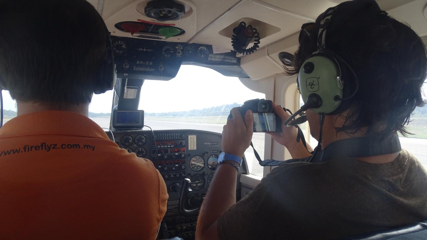 Deux personnes dans un hélicoptère faisant un inventaire aérien pour repérer des dauphins de Guyane