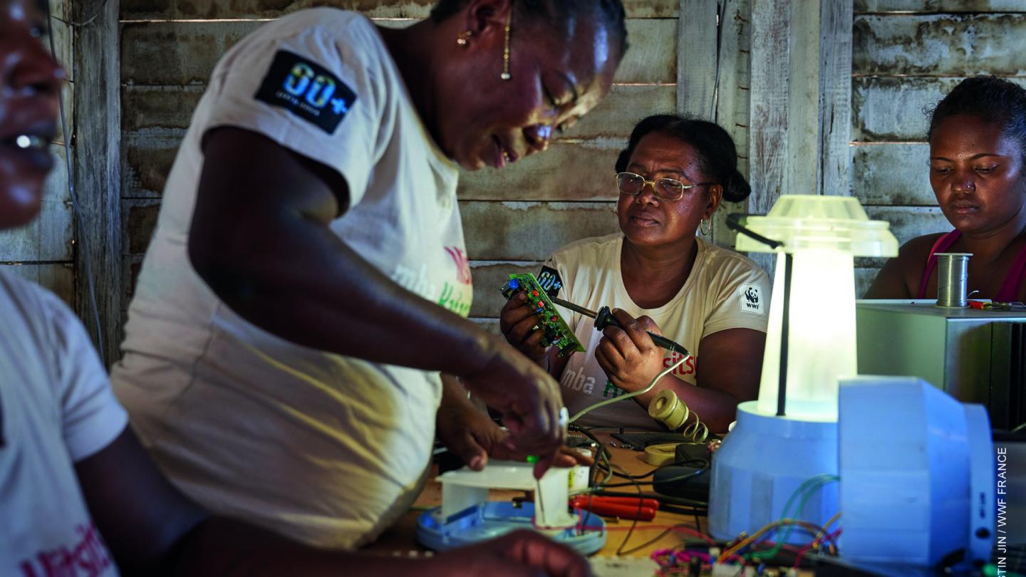 Les grands-mères "solaires" travaillent à l'installation de batteries, de régulateurs et lampes LED pour illuminer leur village d'Ambakivao (Madagascar)