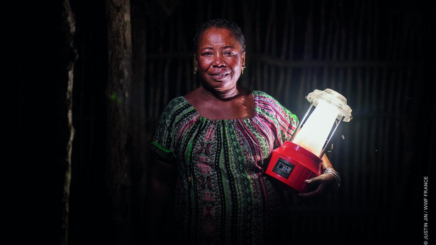 Portrait de Kingeline, une ingénieure en énergie solaire, tenant une lampe solaire.