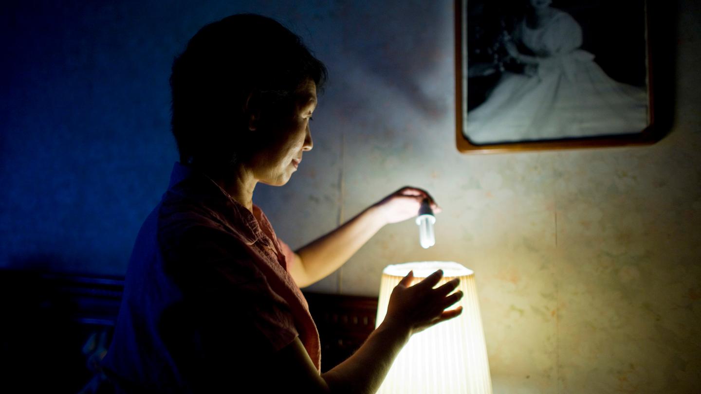 Femme changeant son ampoule basse consommation dans le cadre de la campagne "20 ways to 20%" du WWF (Chine)