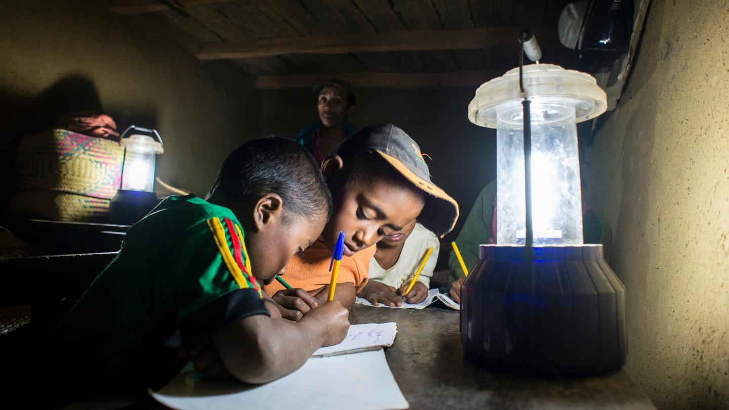 Enfant qui étudie à la lueur d'une lampe solaire à Madagascar