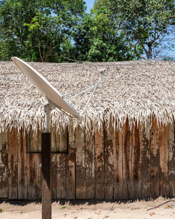 Maison en paille et en bois avec des antennes paraboliques, dans le village de Bela Vista do Capixauã, Aldeia Vista Alegre do Capixauã, Santarém, Pará, Brésil