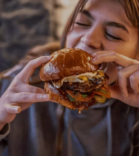 Jeune fille mangeant un hamburger appétissant, défi au mythe des protéines animales