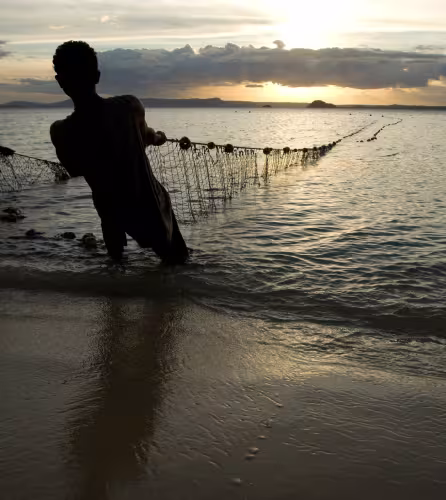 Des pêcheurs sortent leurs filets de l'eau au crépuscule, plage de Ramena à Antsiranana, Nord de Madagascar