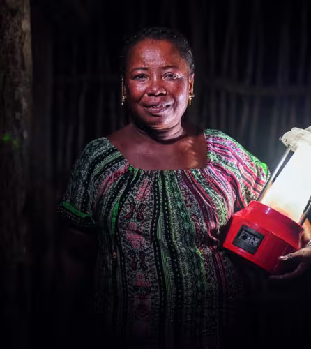Portrait de Kingeline, une ingénieure en énergie solaire, tenant une lampe solaire.