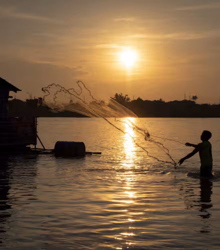 Un pêcheur lance son filet alors que le soleil se couche sur le fleuve Mékong, à Vientiane, RDP Lao.
